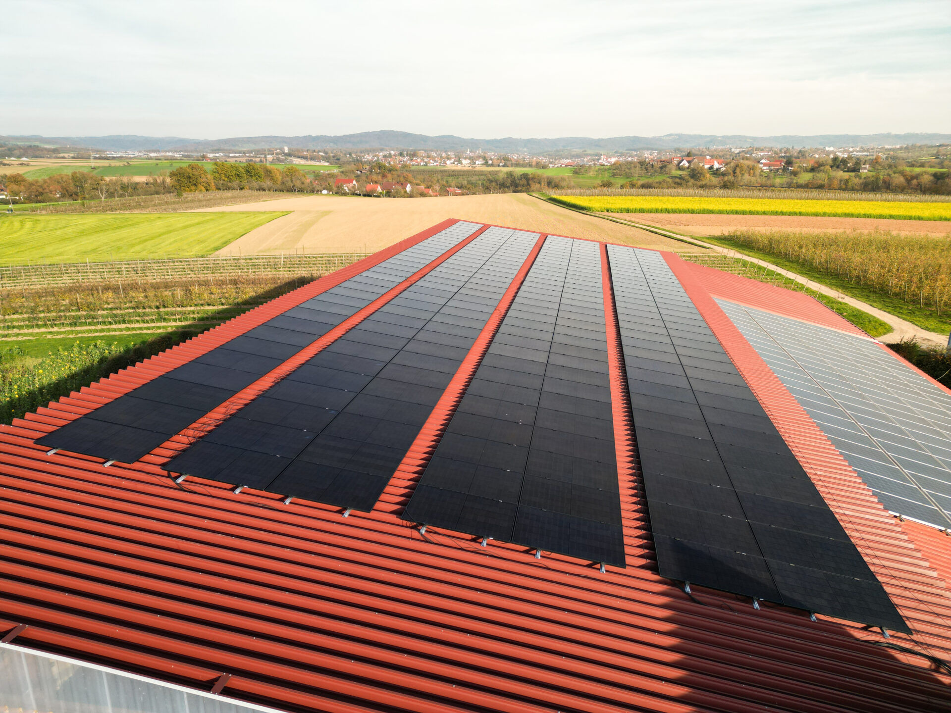Drohnenansicht auf eine Photovoltaikanlage auf dem Dach einer Halle bei Sonnenschein
