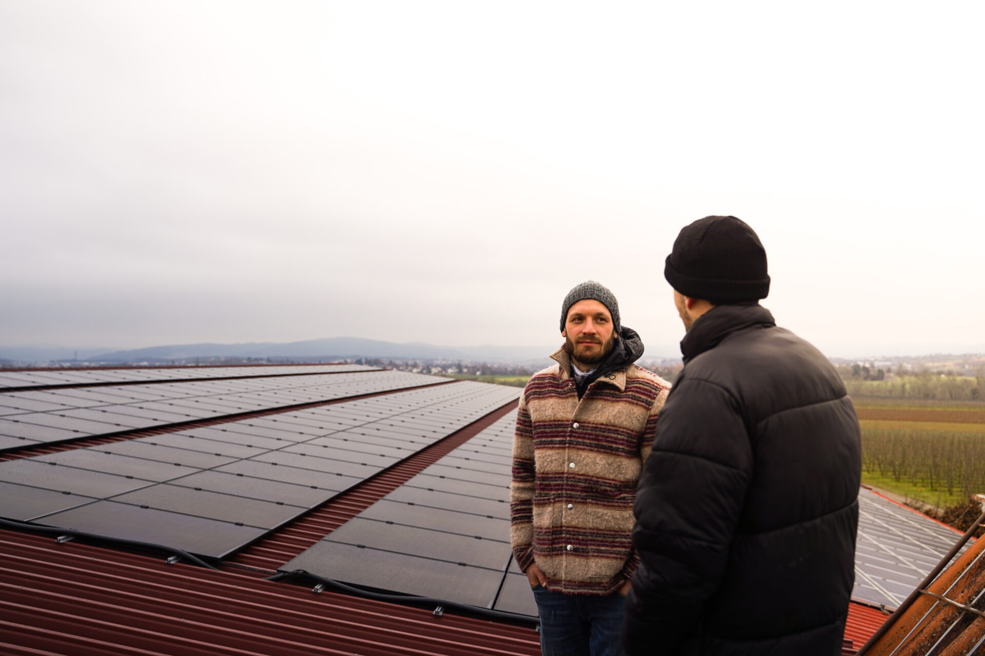 Zwei Männer vor der Photovoltaikanlage auf dem Dach einer Halle
